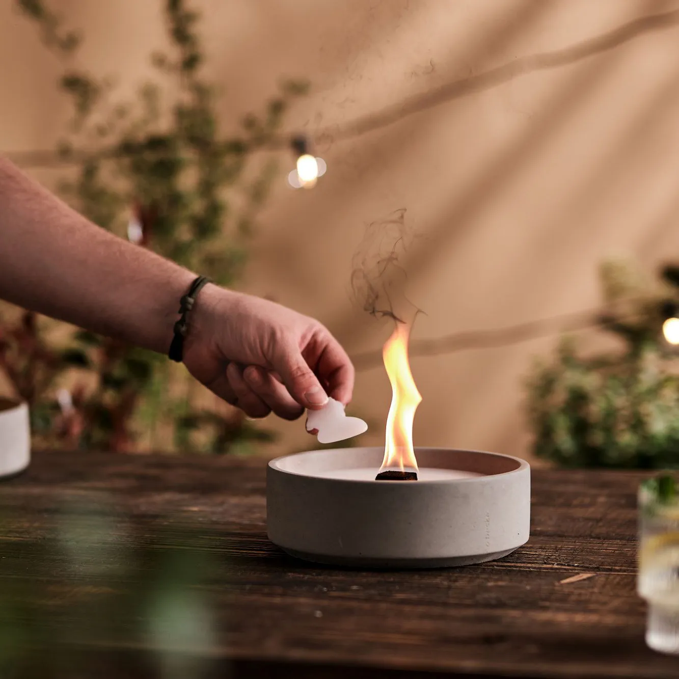 Wachsnachlegen bei Betonfeuer Suma-L auf Holztisch im Garten gemütliche Stimmung