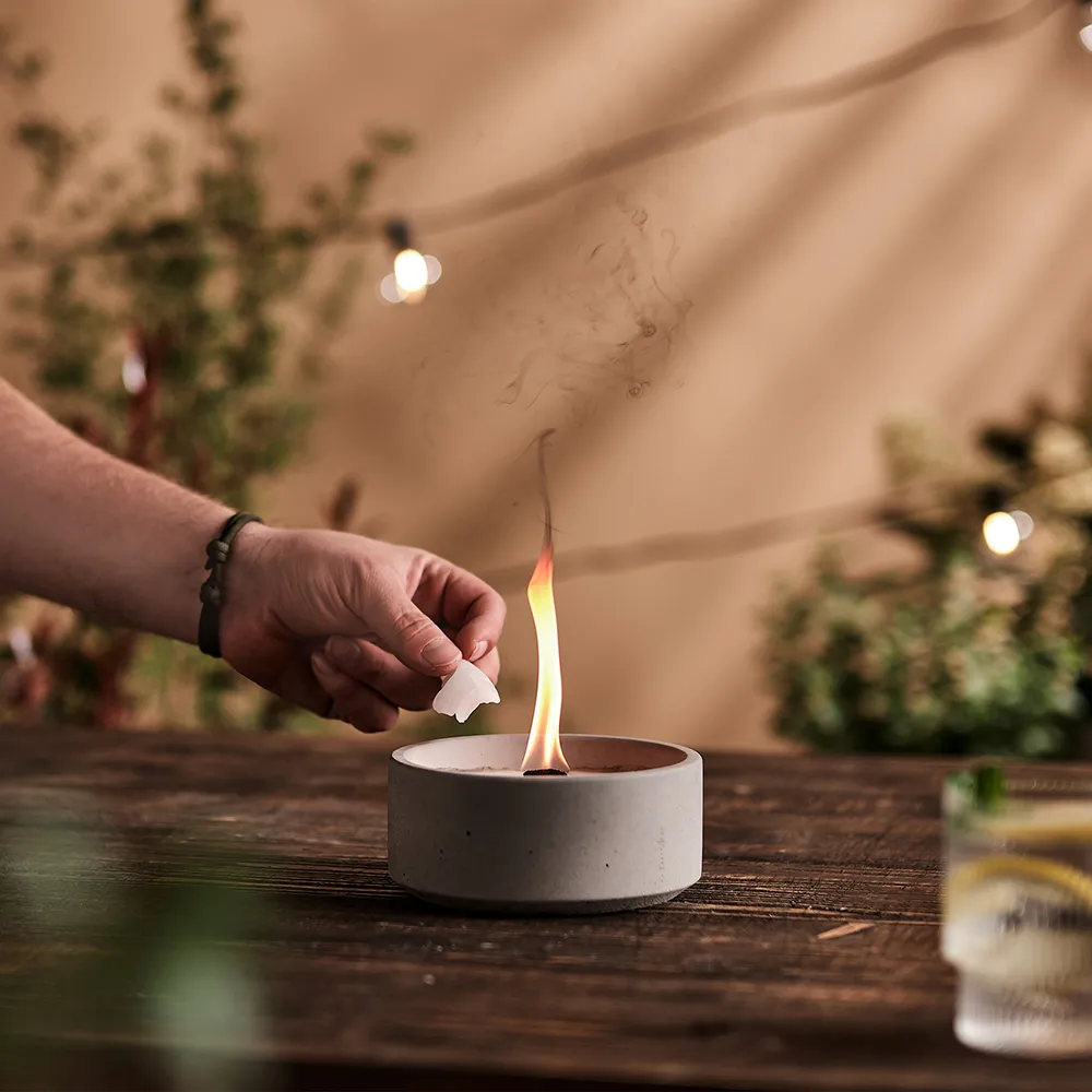 Nachlegen von Wachs in das Betonfeuer Suma-M in Szene mit gemütlicher Stimmung